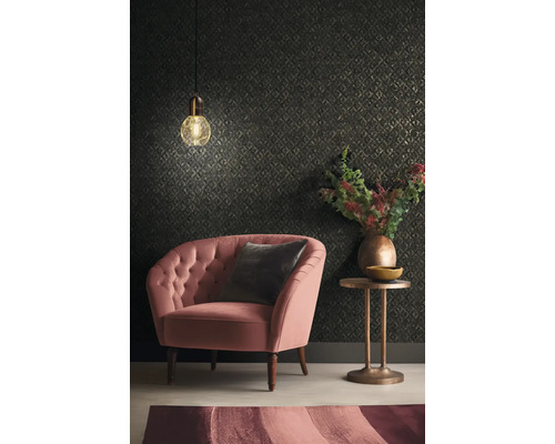 Woonkamer met fauteuil, kussen, bijzettafel, lamp en behang met patroon.