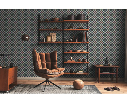 Woonkamer met behang met patroon, planken, fauteuil, tapijt en houten vloer.