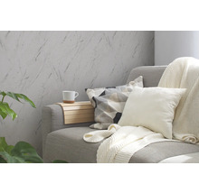 Woonkamer met grijze bank, kussens, deken en wandbekleding in marmerlook