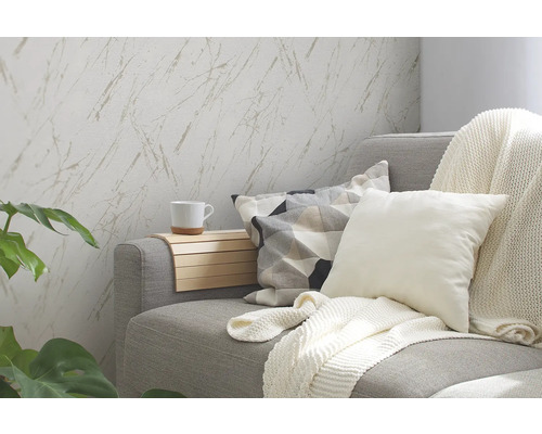 Woonkamer met grijze bank, kussens, deken, bijzettafel en behang met marmerpatroon.