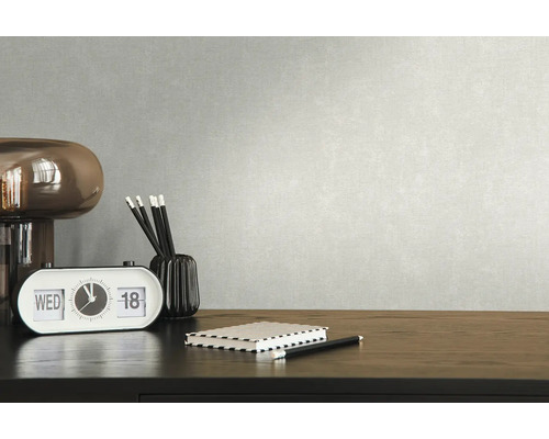 Close-up van een bureau met bureaulamp, kalender, notitieblok, pennenhouder en pennen tegen een gestructureerde muur.