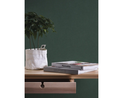 Decoratief stilleven met plant in papieren zak, boeken en houten bureau