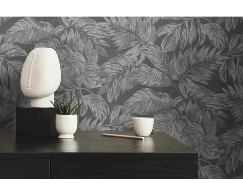 Decoratief stilleven met bladbehang, beeld en plant op een tafel.