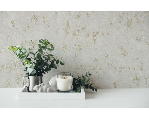 Decoratieve opstelling met patroonbehang, kaars, plant en decoratief object op een tafel.
