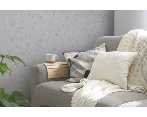 Woonkamer met grijs structuurbehang, bank, kussens en decoraties.