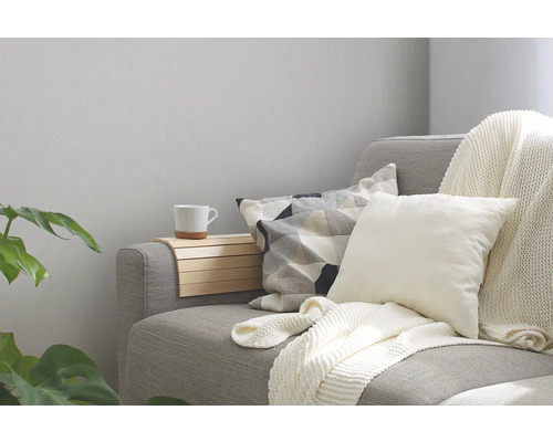 Grijze bank met kussens, plaid en armleuningbak in de woonkamer.