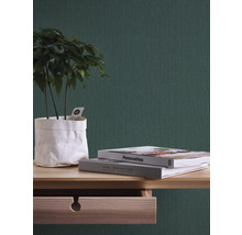 Close-up van een kamer met groen behang, een houten tafel, boeken en een kamerplant.