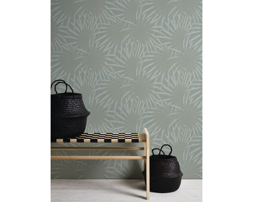 Behang met plantenmotief achter een bank met twee zwarte manden