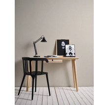 Bureau met zwarte stoel, bureaulamp en decoratieve afbeeldingen op een houten oppervlak.