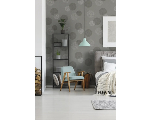 Slaapkamer met bed, fauteuil, rek en behang met cirkelpatroon