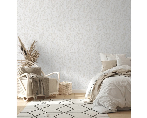 Lichte slaapkamer met bloemenbehang, fauteuil en bed.