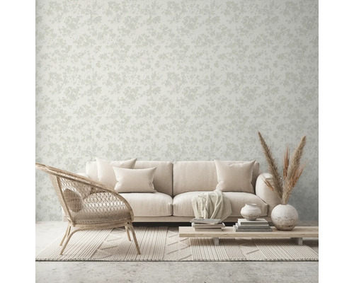 Woonkamer met bank, stoel, tafel en behang met bloemenmotief.