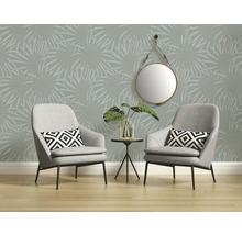 Kameroverzicht met twee grijze fauteuils, kleine tafel met plant, ronde spiegel en behang met palmmotief