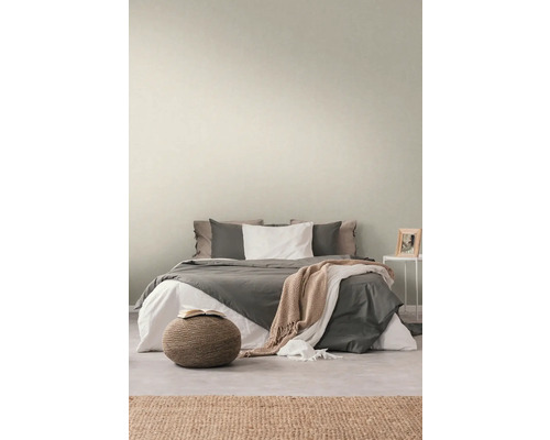 Slaapkamer met bed, nachtkastje, vloerkleed en hocker voor een gezellige sfeer