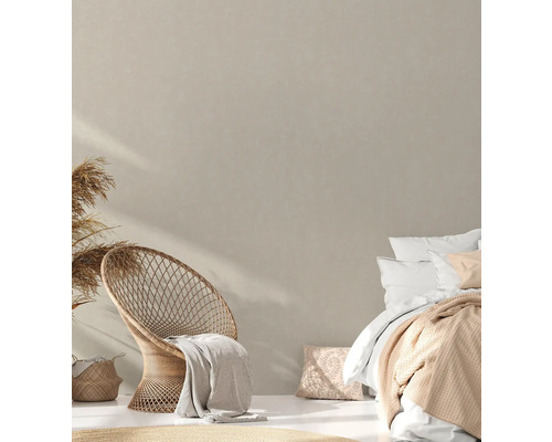 Lichte slaapkamer met rotan stoel, bed en decoratieve elementen voor een gezellige sfeer.