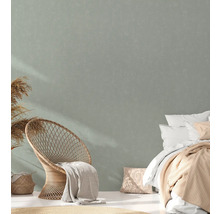 Lichte kamer met rotan stoel, bed en textiel voor een gezellige sfeer.