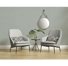 Twee grijze fauteuils met een ronde spiegel en een bijzettafel in een lichte ruimte.