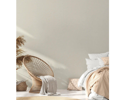 Licht ontworpen slaapgedeelte met rotan stoel en tweepersoonsbed.