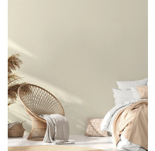 Lichte slaapkamer met rotan stoel, bed en decoratief textiel voor een gezellige sfeer