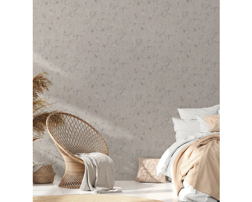 Slaapkamer met rotan stoel en bed voor een wand met structuurbehang.