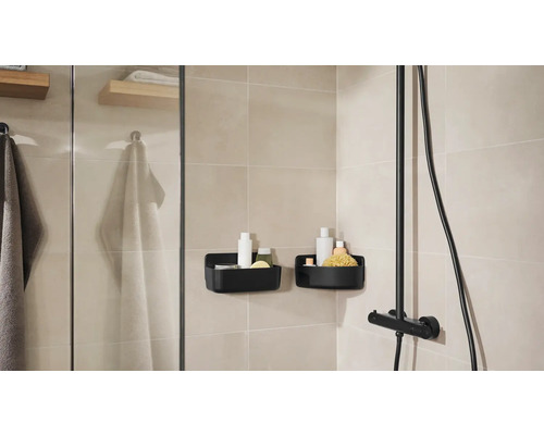 Badkamer met douche, handdoeken en twee zwarte douchebakken voor het opbergen van badartikelen