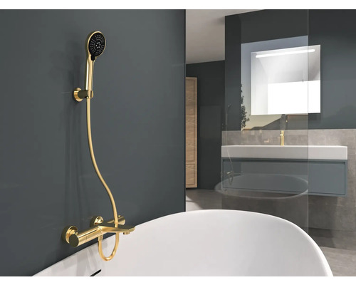 Badkamer met bad, wastafel en gouden douchearmatuur.