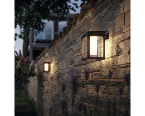 Buiten wandlampen aan een stenen muur verlichten een tuin