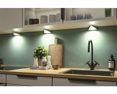 Keukenscène met onderbouwverlichting, gootsteen, kraan en keukengerei op een aanrechtblad