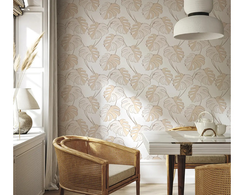 Lichte eetkamer met monstera blad behang, rotan stoel en eettafel.
