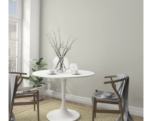 Lichte, vriendelijke eethoek met ronde tafel, twee stoelen, decoratie en kamerplant.