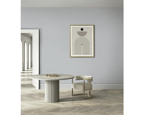 Licht interieur met een ronde eettafel, een stoel en een ingelijste kunstdruk aan de muur