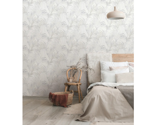 Een slaapkamer met een muur versierd met een behang met plantenmotief, een bed en een stoel.
