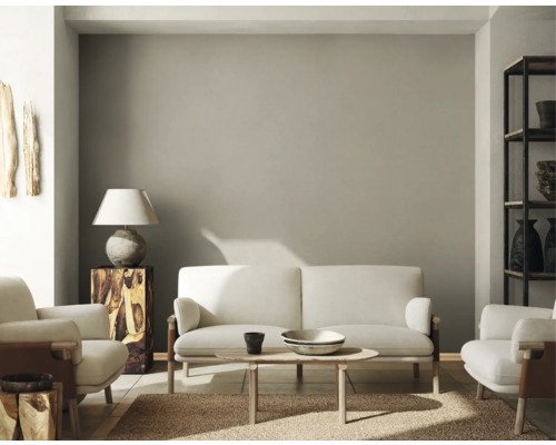 Woonkamer met bank, fauteuils, tafel, lamp en plank.