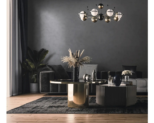 Woonkamer met bank, tafel en kamerplant onder een decoratieve lamp