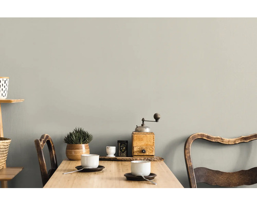 Woonkamer met tafel, stoelen en decoratie voor een grijze muur