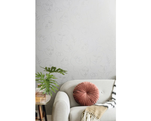 Woonkamer met behang met vrouwengezichten, bank, kussen, plant en tafel