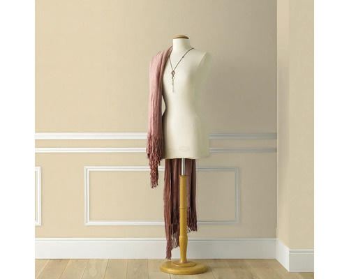 Paspop met sjaal en ketting voor een muur met sierlijsten