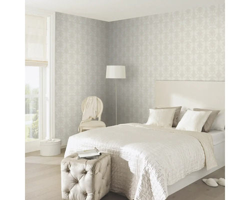 Slaapkamer met bed, stoel, vloerlamp en behang met motief