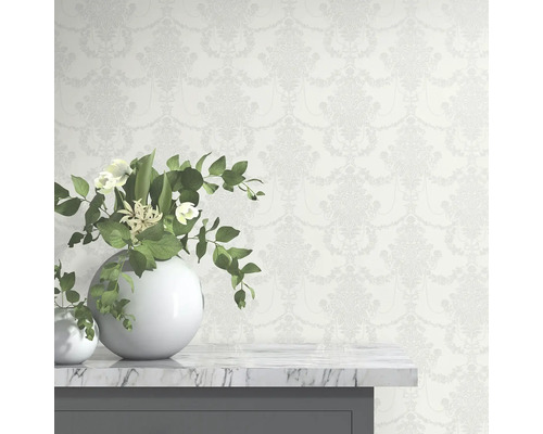 Behang met bloemmotief achter witte vazen op een tafel.