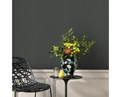 Decoratieve woonkamer met zwart designbehang in houtlook, een bijzettafel met bloemenvaas en een designstoel.