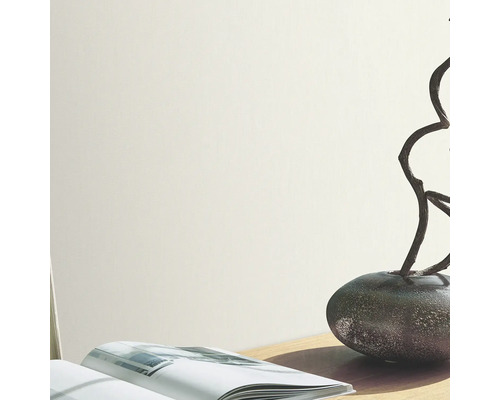 Lichte muur met vaas, takken en boek op een tafel.