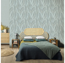 Slaapkamer met bladerenbehang, rotan bedframe en houten vloer