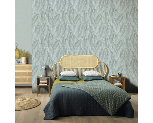 Slaapkamer met bladerenbehang, rotan bedframe en houten vloer