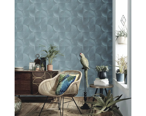 Woonkamer met geometrisch behang, rotan stoel, houten dressoir en kamerplanten