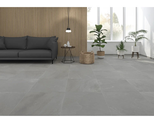 Woonkamer met grijze vloertegels, bank en planten.