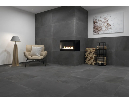 Woonkamer met antracietkleurige tegels, open haard, fauteuil en staande lamp