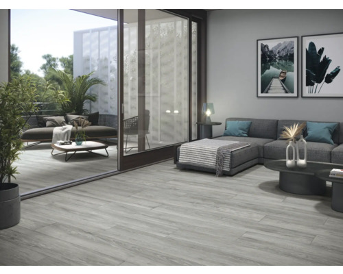 Woonkamer met grijze houtlook vloertegels en toegang tot het balkon