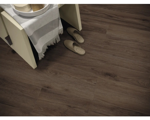 Interieurfoto van een kamer met laminaat in houtlook, een kleine kruk en pantoffels.