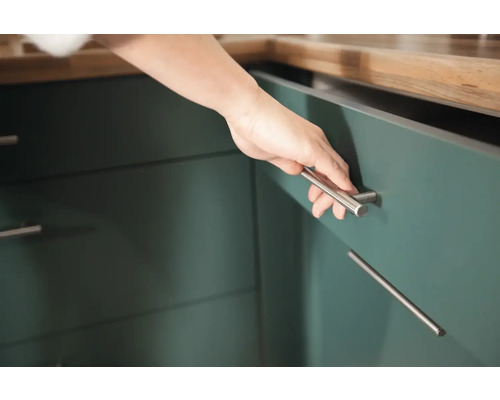 Close-up van een hand die een keukenkast opent met een zilveren handgreep.