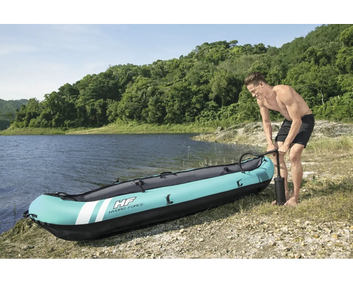 Man pompt een opblaasbare kajak op de oever op.